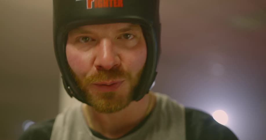 A man wearing padded headgear and a mouth guard has a look of determination on his face