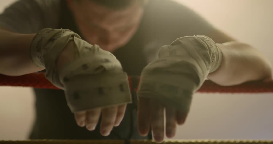 White boxer rests his hand on ropes to get rest in the boxing ring