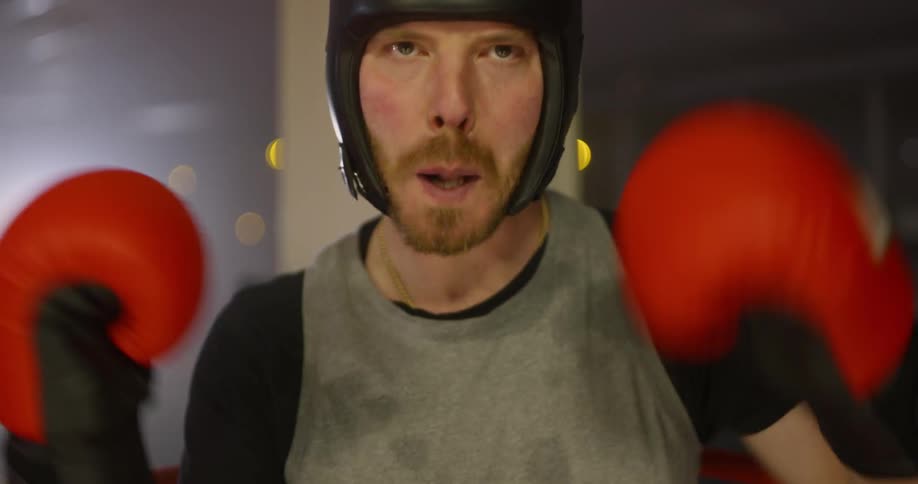 Male boxer sanding in the corner of boxing ring wears a blue protective mouthguard and goes on to fight