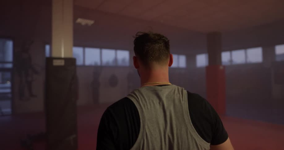 A man with boxing gloves walking in a indoor gym