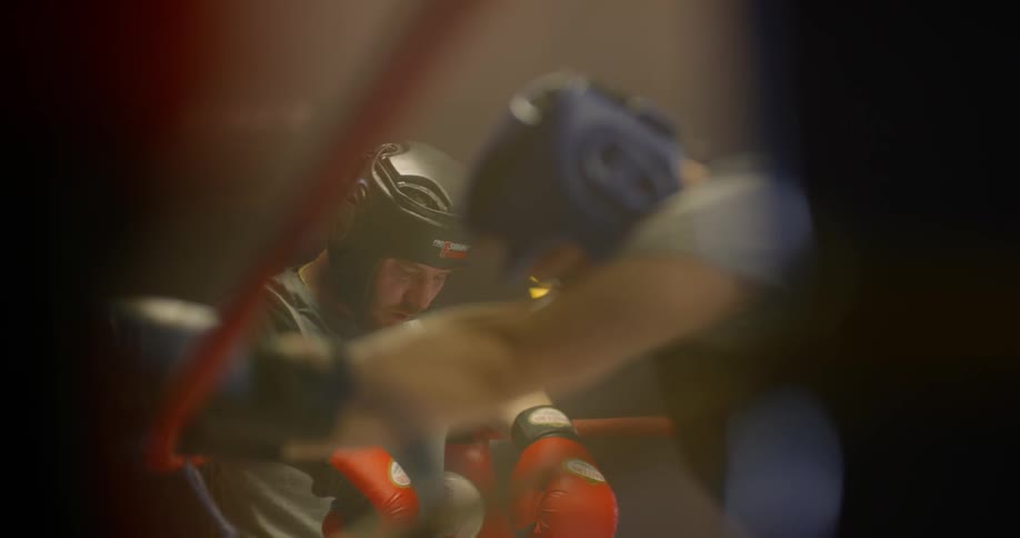 Two boxers resting their hands on the boxing ropes have a break to rest in the boxing ring