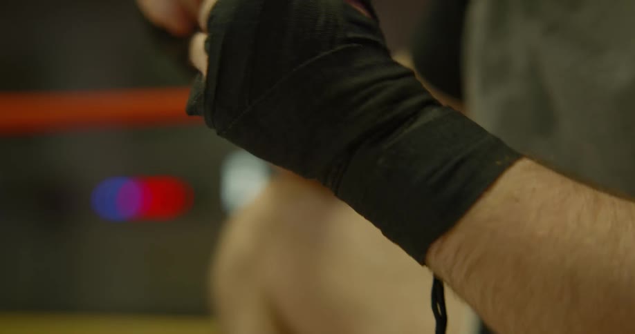 Boxer takes off one of the gloves off in the boxing ring