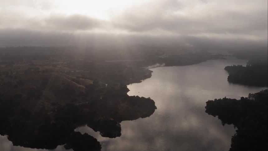 A river through a countryside covered in trees on a cloudy day