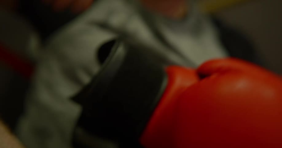 White boxer takes one of the boxing glove off in the ring