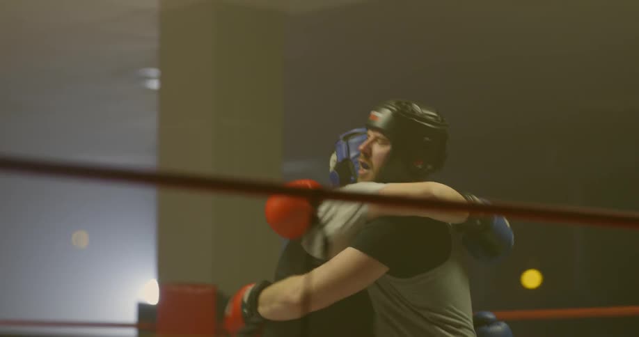 Two men are sparring in a boxing rings and then give one another a hug upon finishing