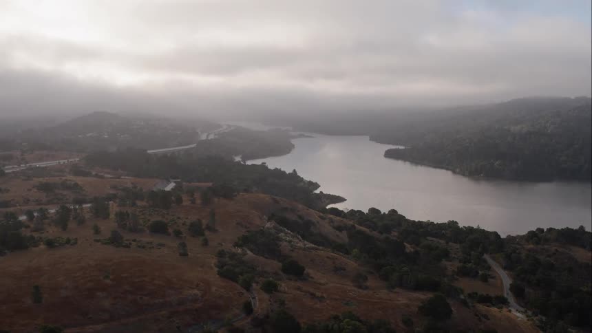 Roads curve along a hill overlooking a lake on a cloudy day