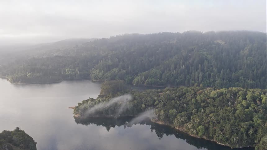 Tree covered hills over a serene lake on a cloudy lake