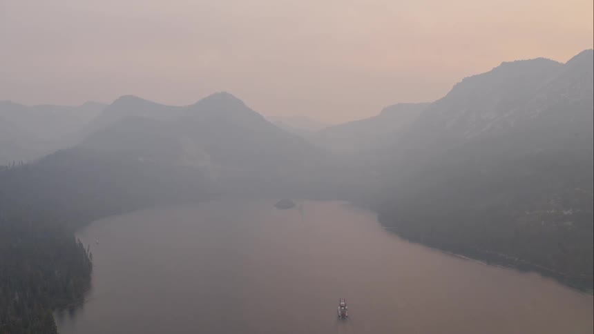 A lake with a boat with mountains in the background