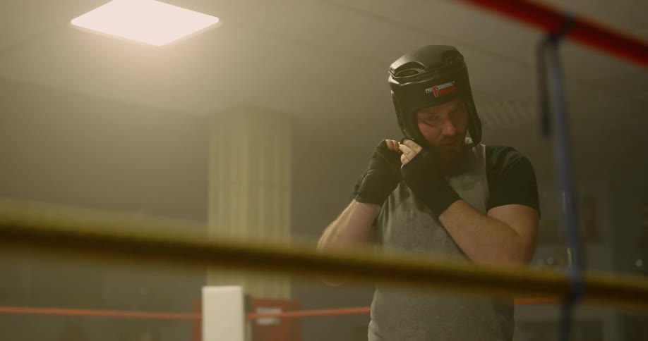 A boxer puts his gear on while standing in a boxing ring