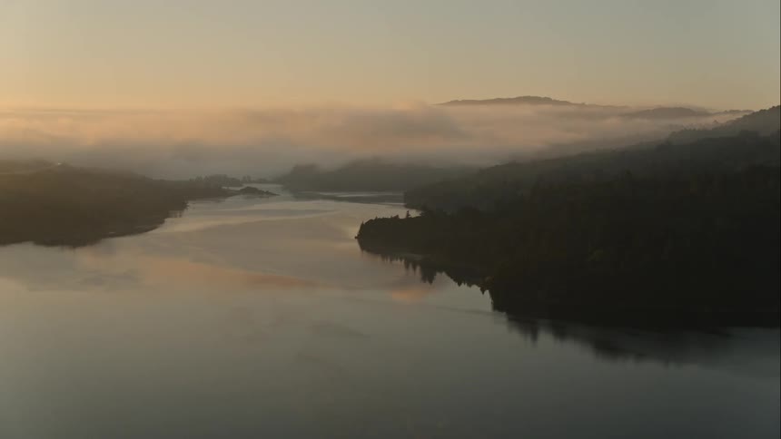 The sun starts to rise over a calm large lake