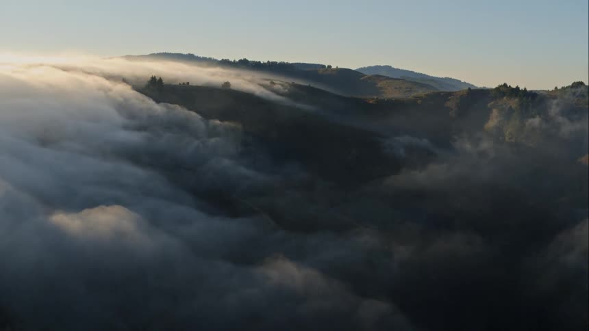 Fog rolling across a hilly terrain