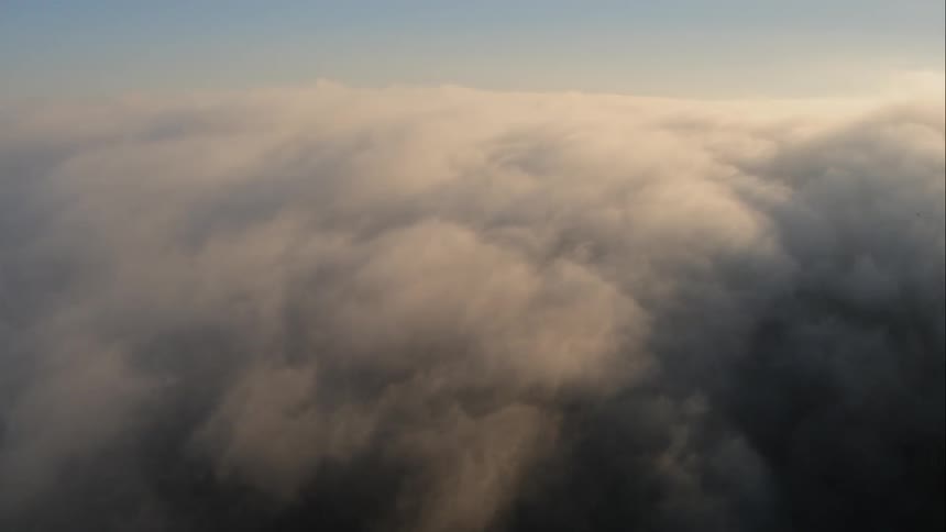 High in the sky a dense layer of fluffy clouds completely obscures the landscape below