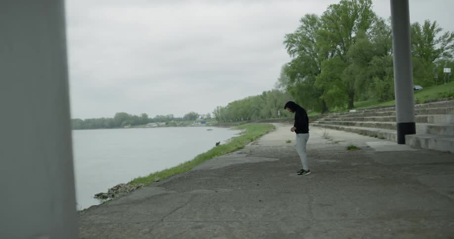 A man runs down some stairs and stretches and boxes in front of the water