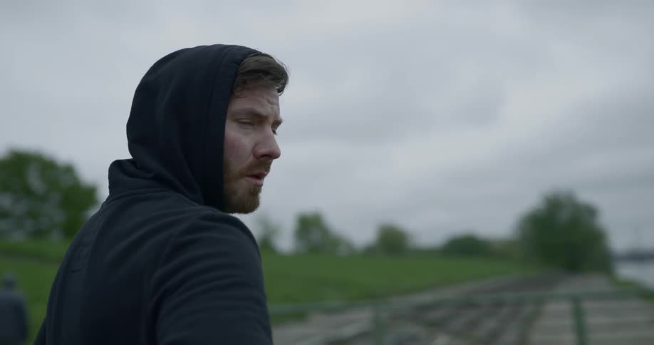 A man stands near the water and looks around him