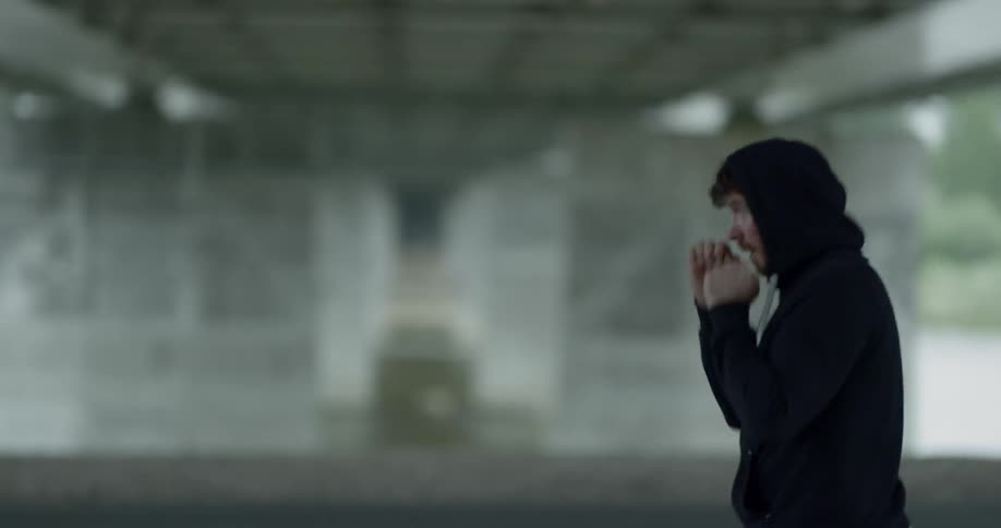 Man in black hoodie practices punching and trains alone under the bridge