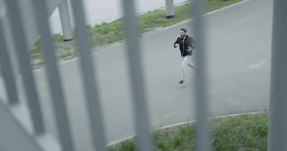 Man jog along path under bridge and stairway