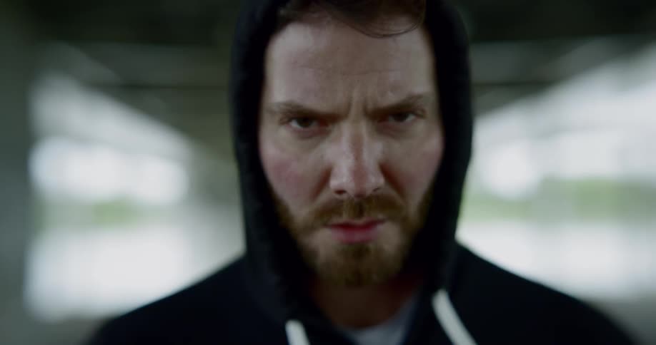 Man in hoodie stands in well lit room