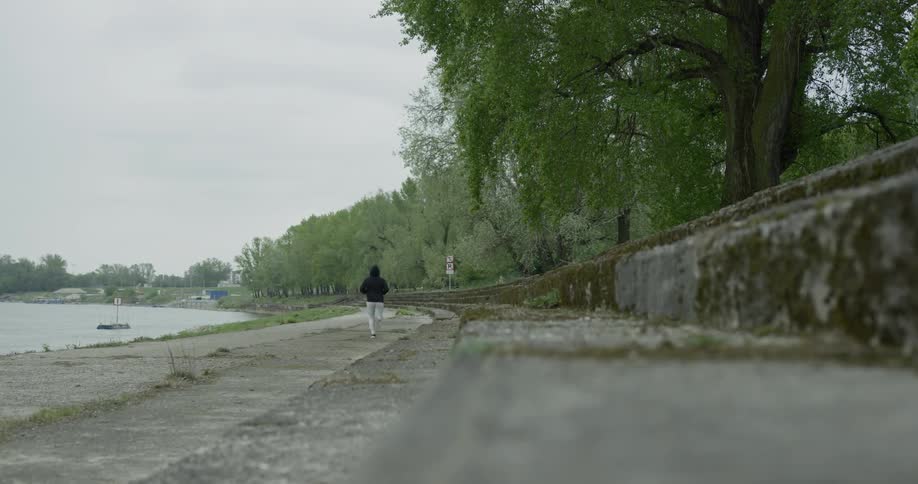 A man jogs on a trail along the shore