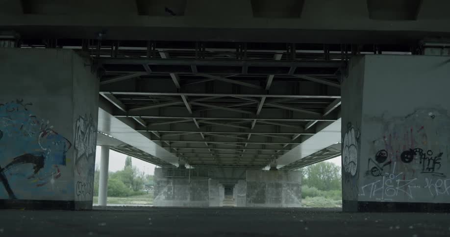Man in black hoodie runs under the bridge during the day