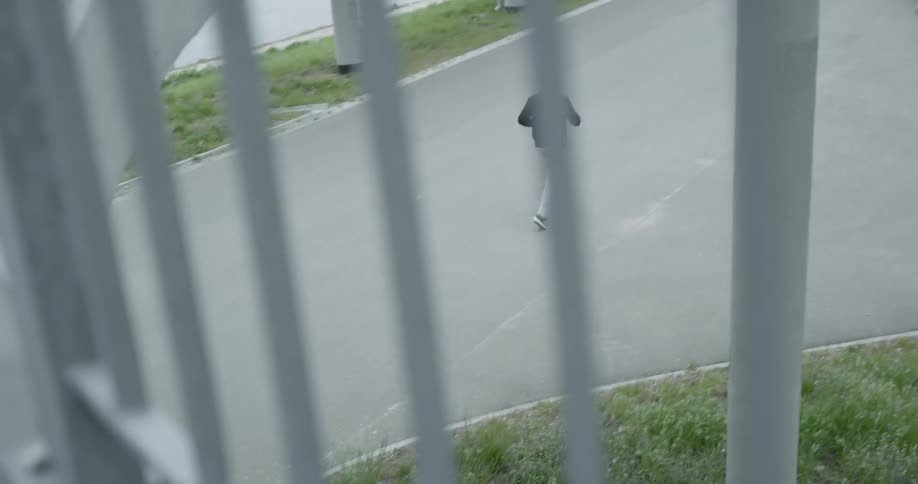 Man wearing a black hoodie runs along the asphalt road on a cloudy day
