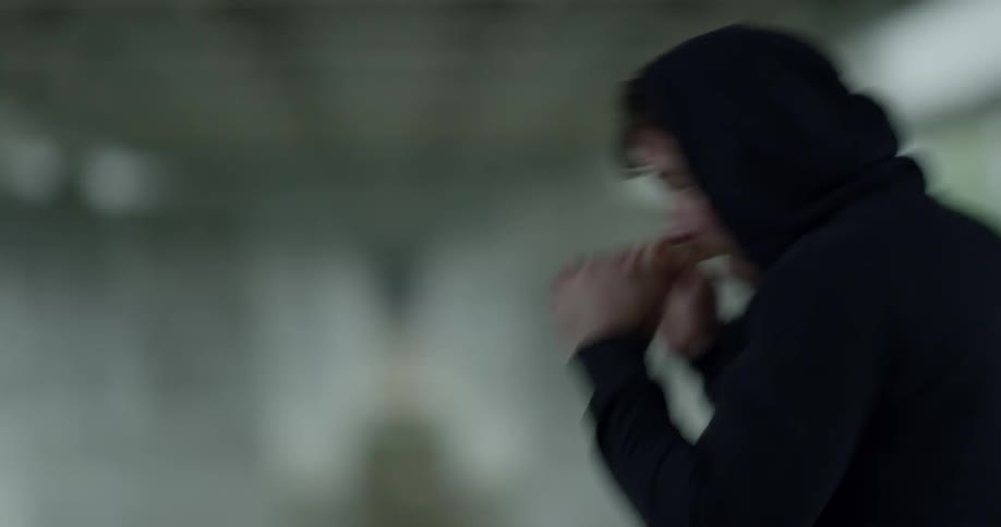 A man practices boxing moves under a bridge outdoors