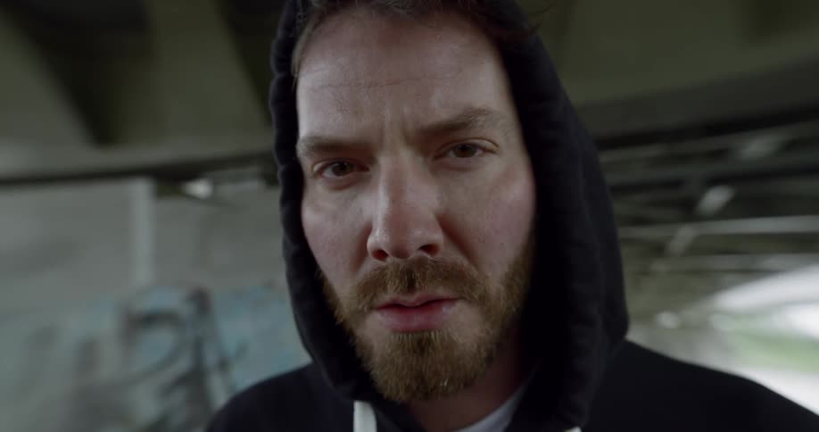 Bearded white boxer in hoodie looks at the camera angrily in the building