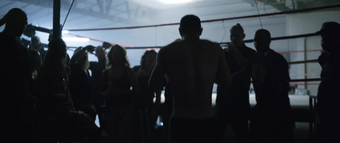 A boxer makes his way toward the ring through a crowd of onlookers