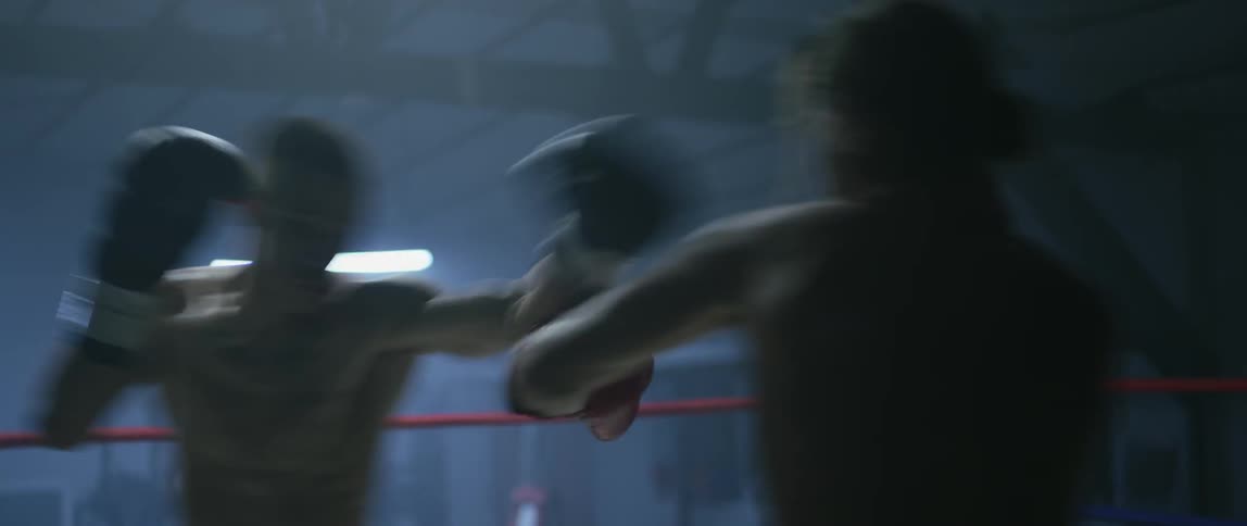 Two men boxing in a ring as others stand by and watch