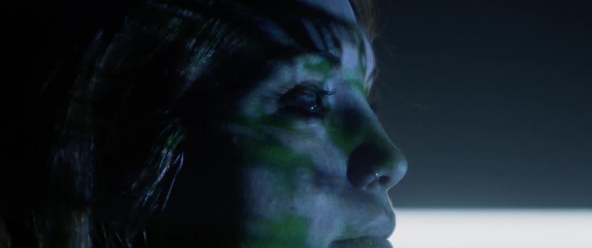 A young woman looks ahead as lights shine on her face