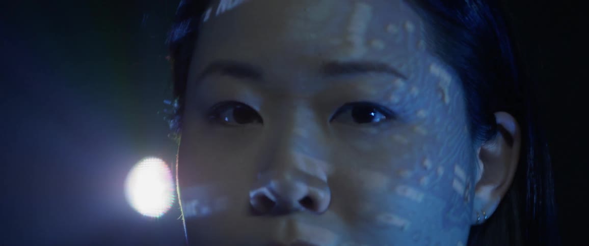 Asian woman in dark room with words projecting on her face