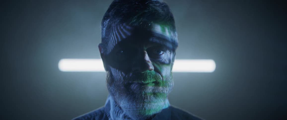 A man sits in front of a screen which reflects light on to his face