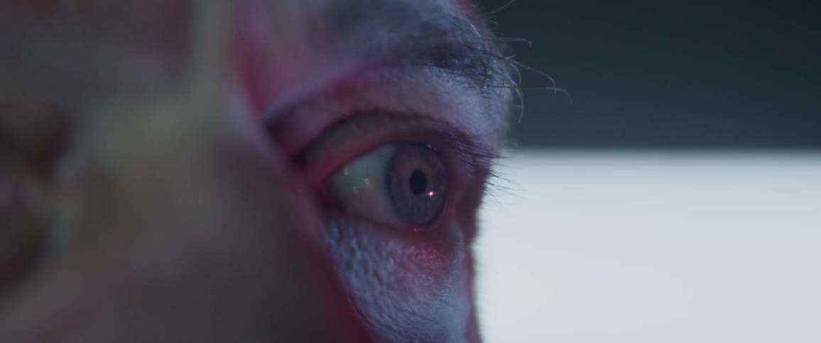 A close up of a man looking at a screen with fast moving images reflecting onto him