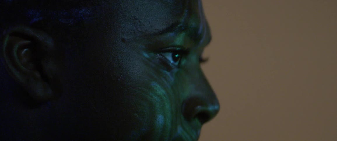 Words and colored lights are projected on a black mans face