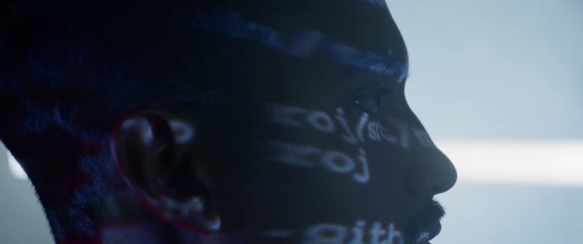 Words in various colors are projected onto a mans face
