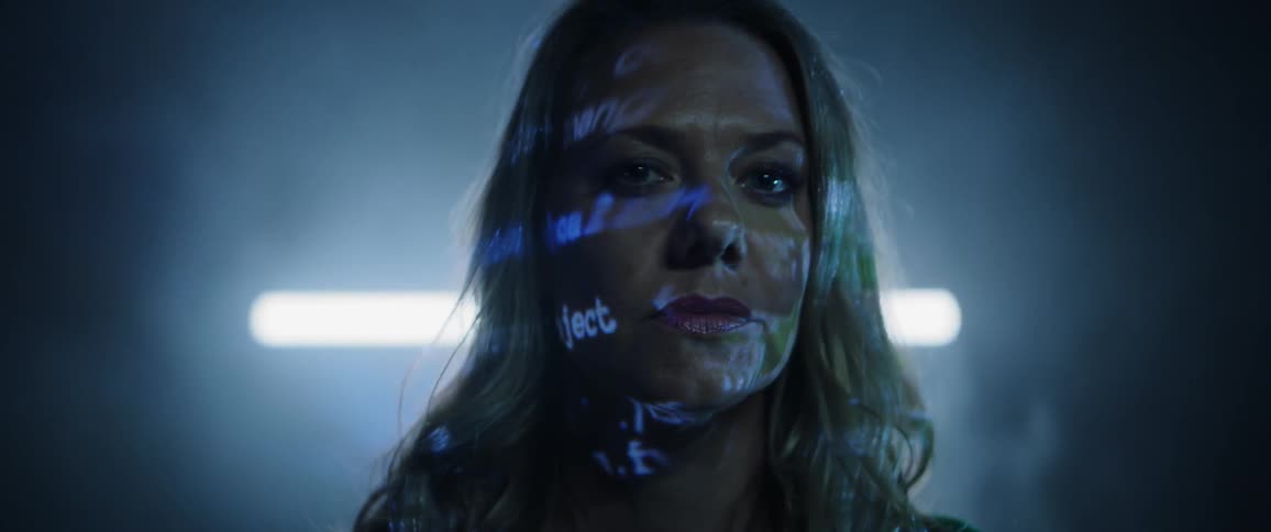 A woman staring with words projected on her face and a light in the background