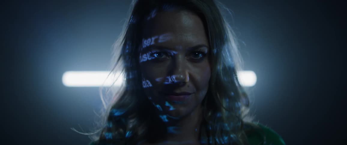 A woman looks ahead as lights reflect on her face