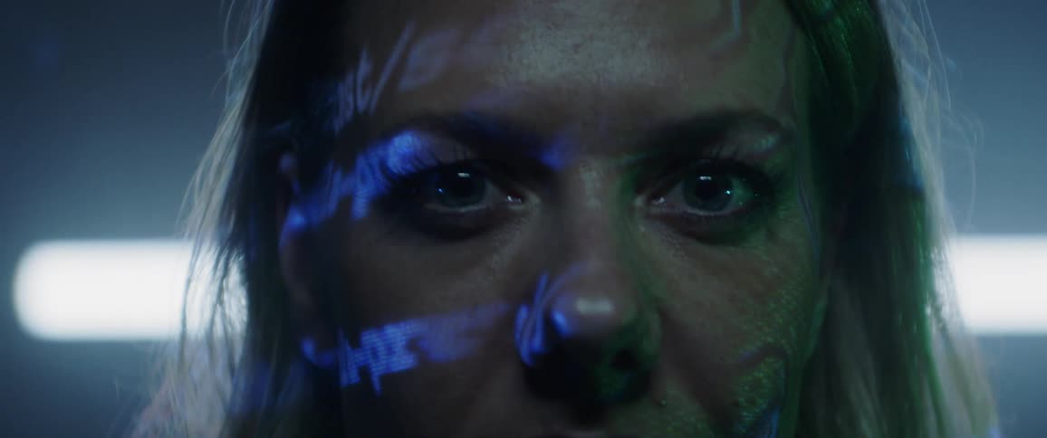 Words and text in light flash on a womans face as she stares straight ahead