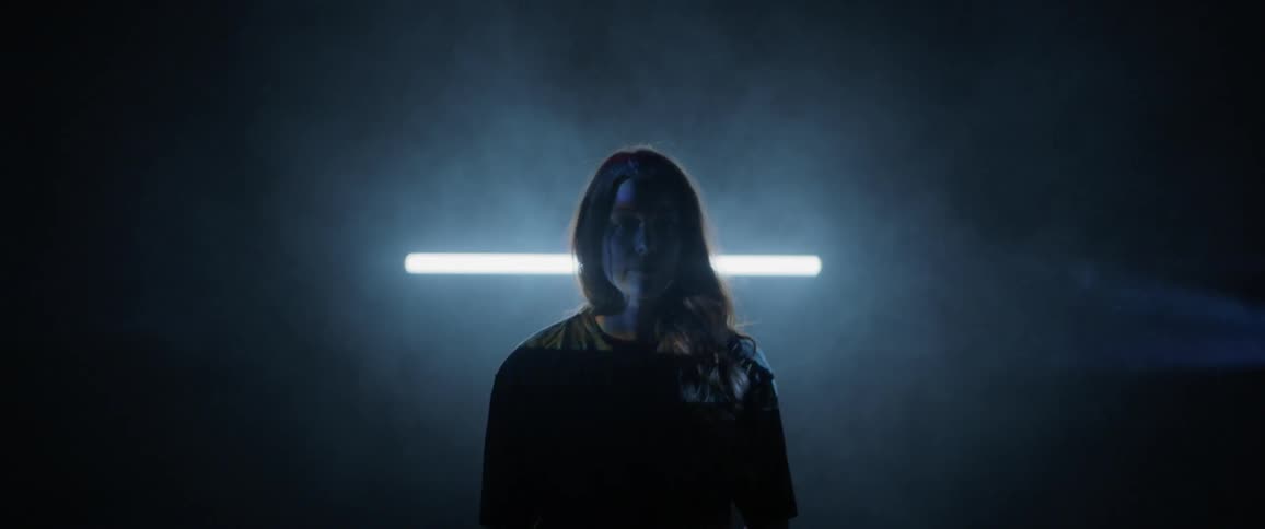 Images projected onto womans face as she stands in dark room