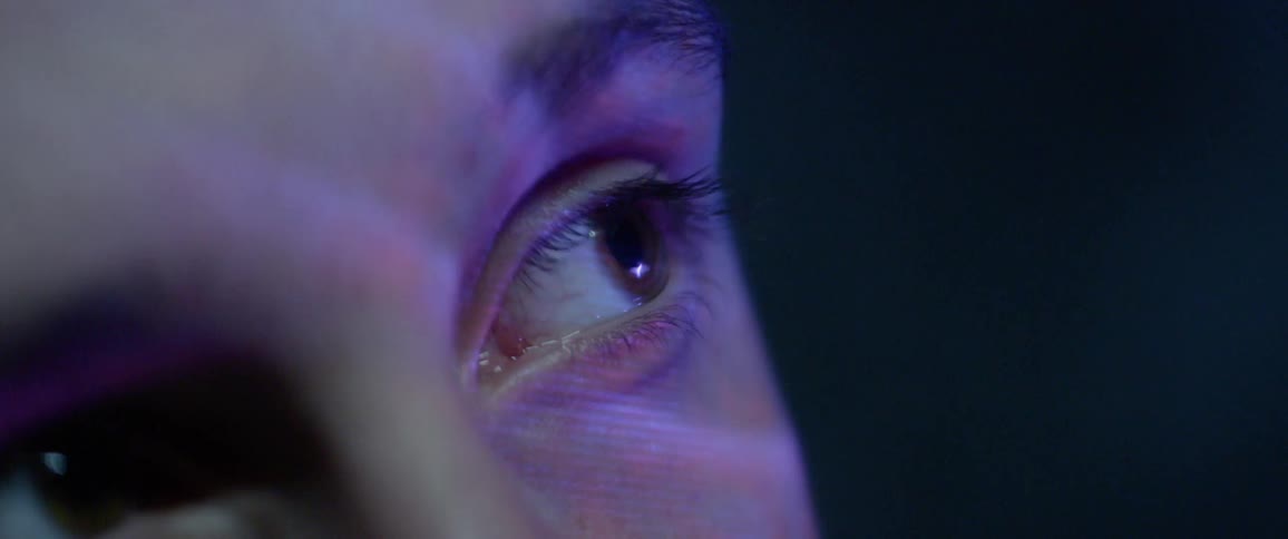 Colorful lights are projected on a womans face and across her eyes