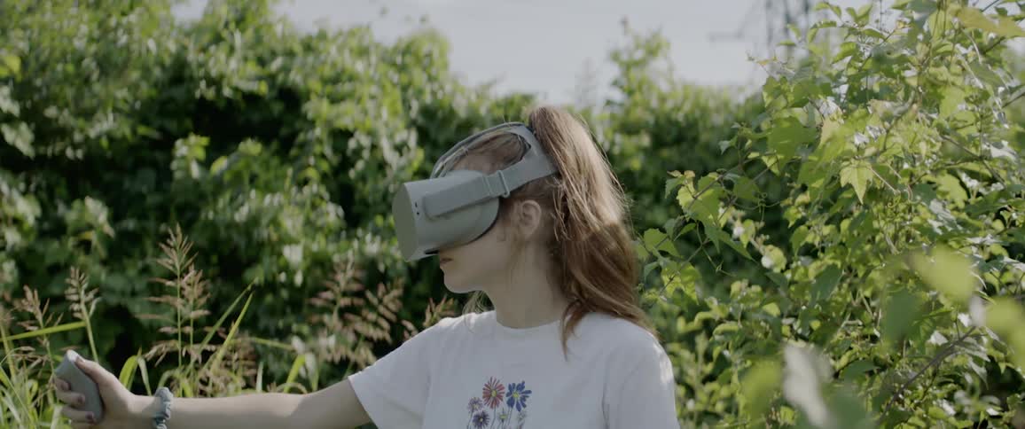 A woman is using a virtual reality headset outside