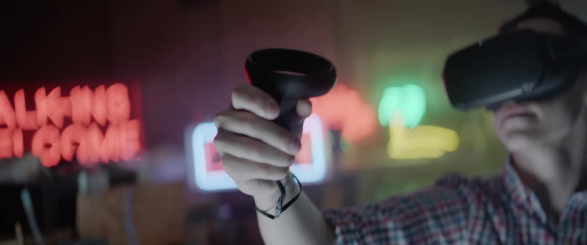 A man moves a controller around in his hand while wearing a vr headset