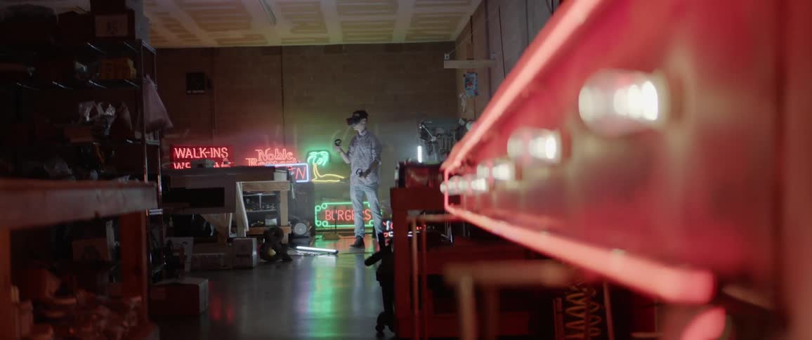 A man uses vr glasses in a room full of neon signs