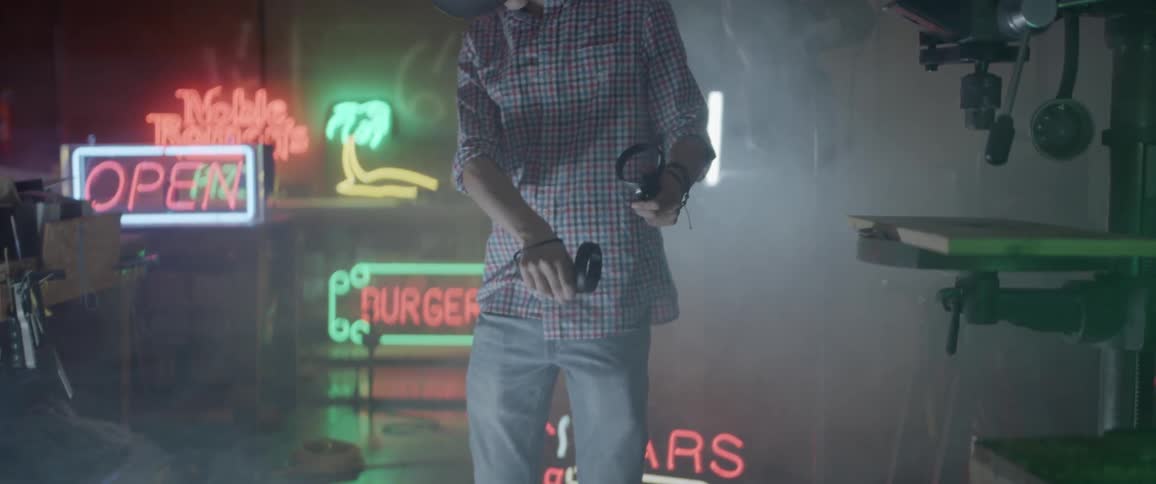 A young male waves his arms around while holding controllers and wearing a virtual reality headset