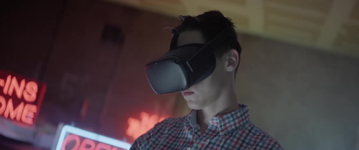 A young man stands in a slightly smoky room as he wears a virtual reality headset
