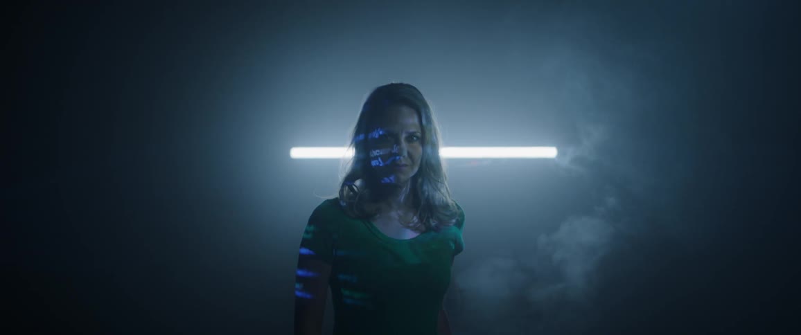 A woman standing in a dark room with words projected on her face