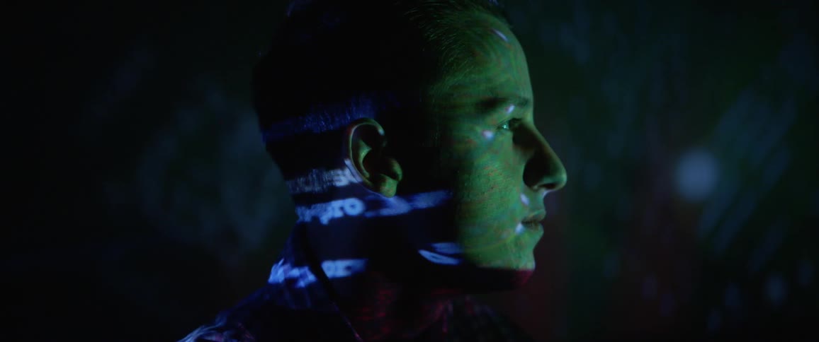 Images and text flash on the face of a man being used as a projection screen