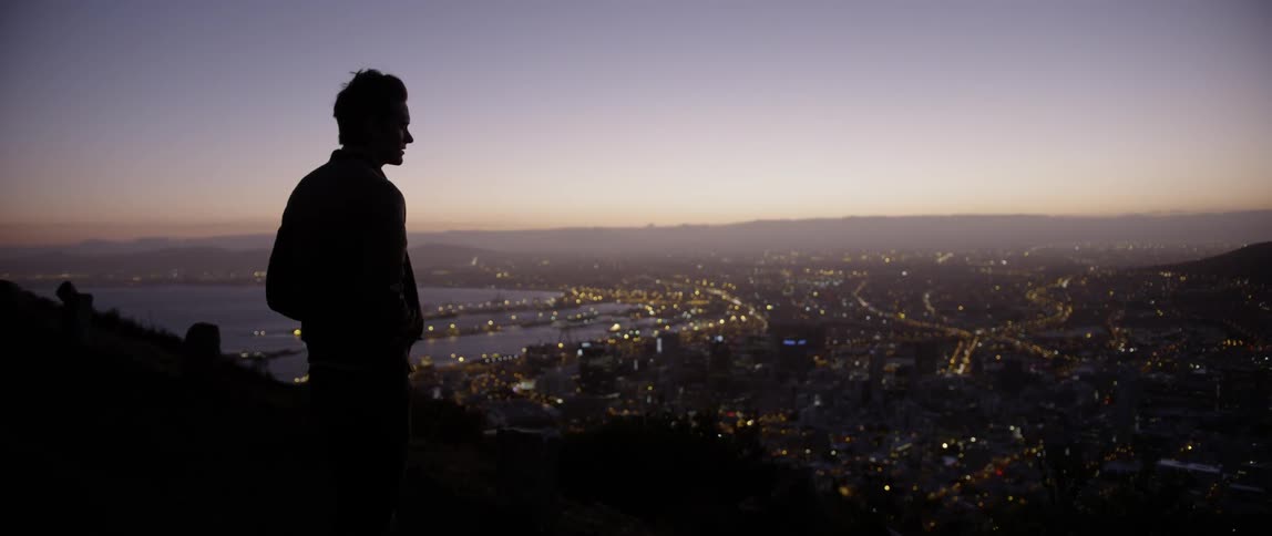 A man stands on the mountain overlooking the city at dawn