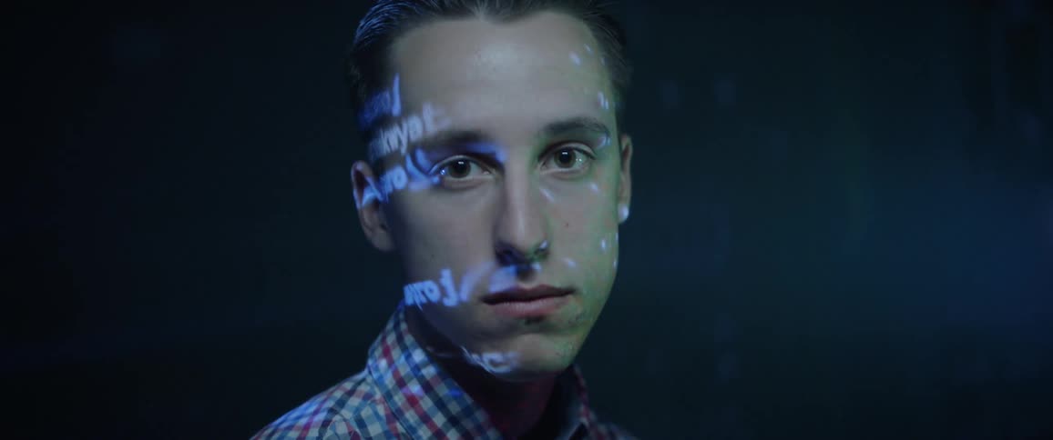 A young man looking at the camera as text is projected on his face