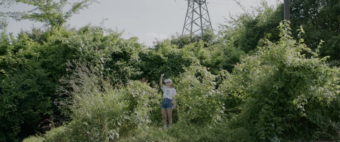 A young girl stands in the trees with virtual reality gear on