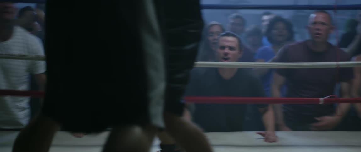 An audience cheers on two boxers